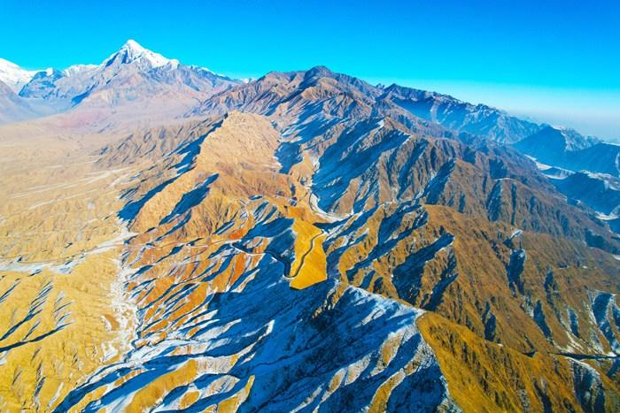 新疆阿克蘇山區(qū)雪后壯美巍峨 陽(yáng)光下群山黃白相間